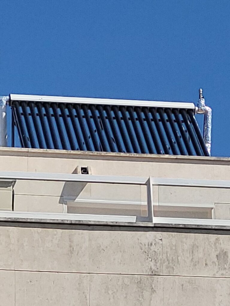 Vista de un sistema de colectores solares de tubos evacuados instalado en el techo de un edificio bajo un cielo despejado.