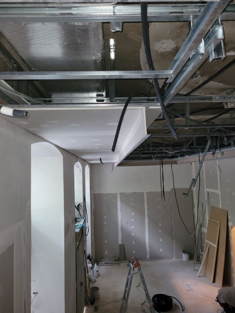 Habitación en construcción con estructura metálica en el techo, paredes sin terminar y herramientas en el suelo.